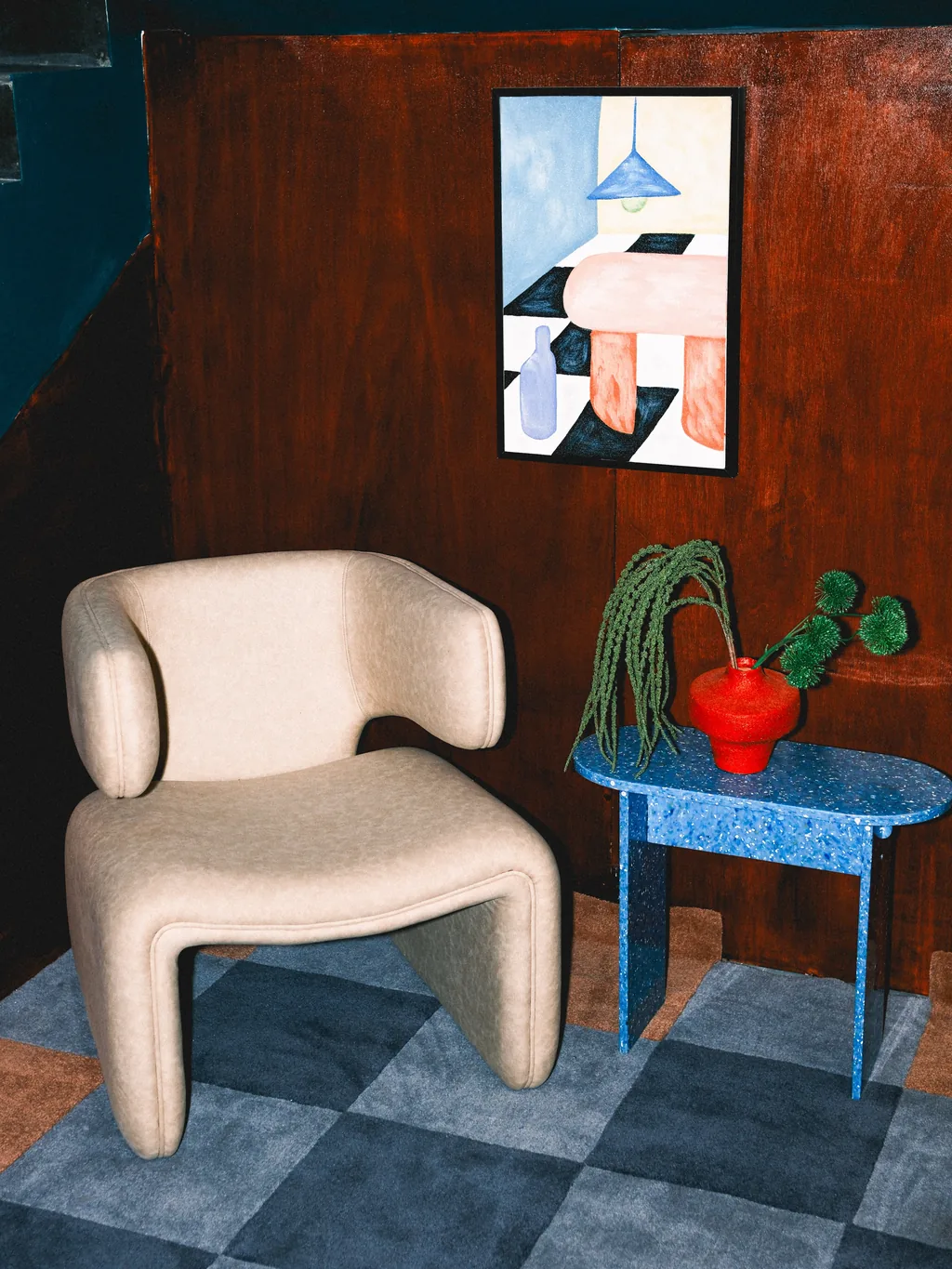An armchair, a blue side table and a painting in a corner of the hotel