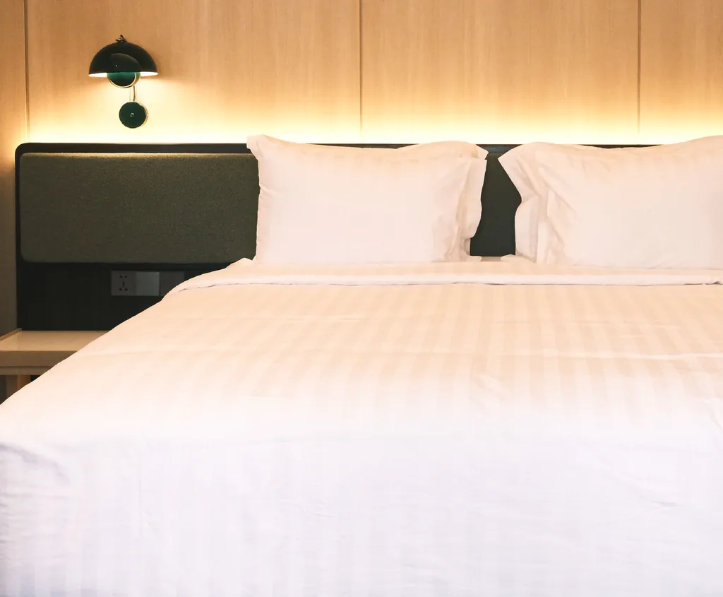 Bed with a green headboard and a wall lamp in the Bossa Nova room