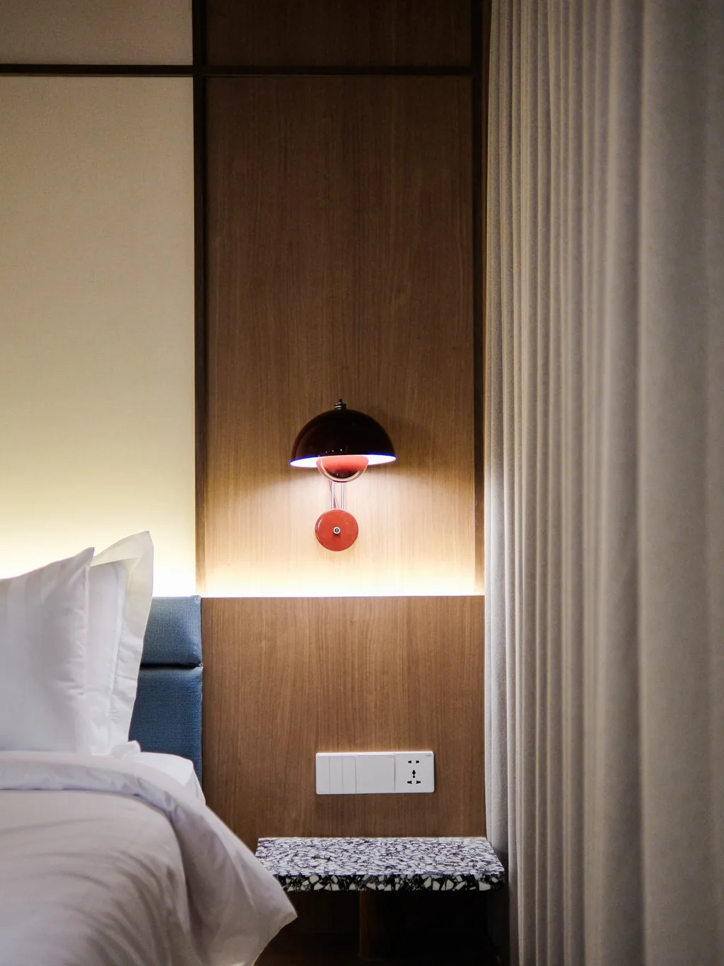 Headboard with a red wall lamp and curtain