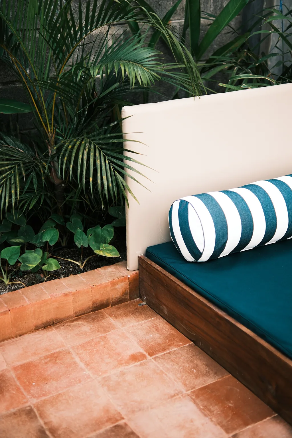 Daybed with a striped cushion on a terracotta terrace among palms