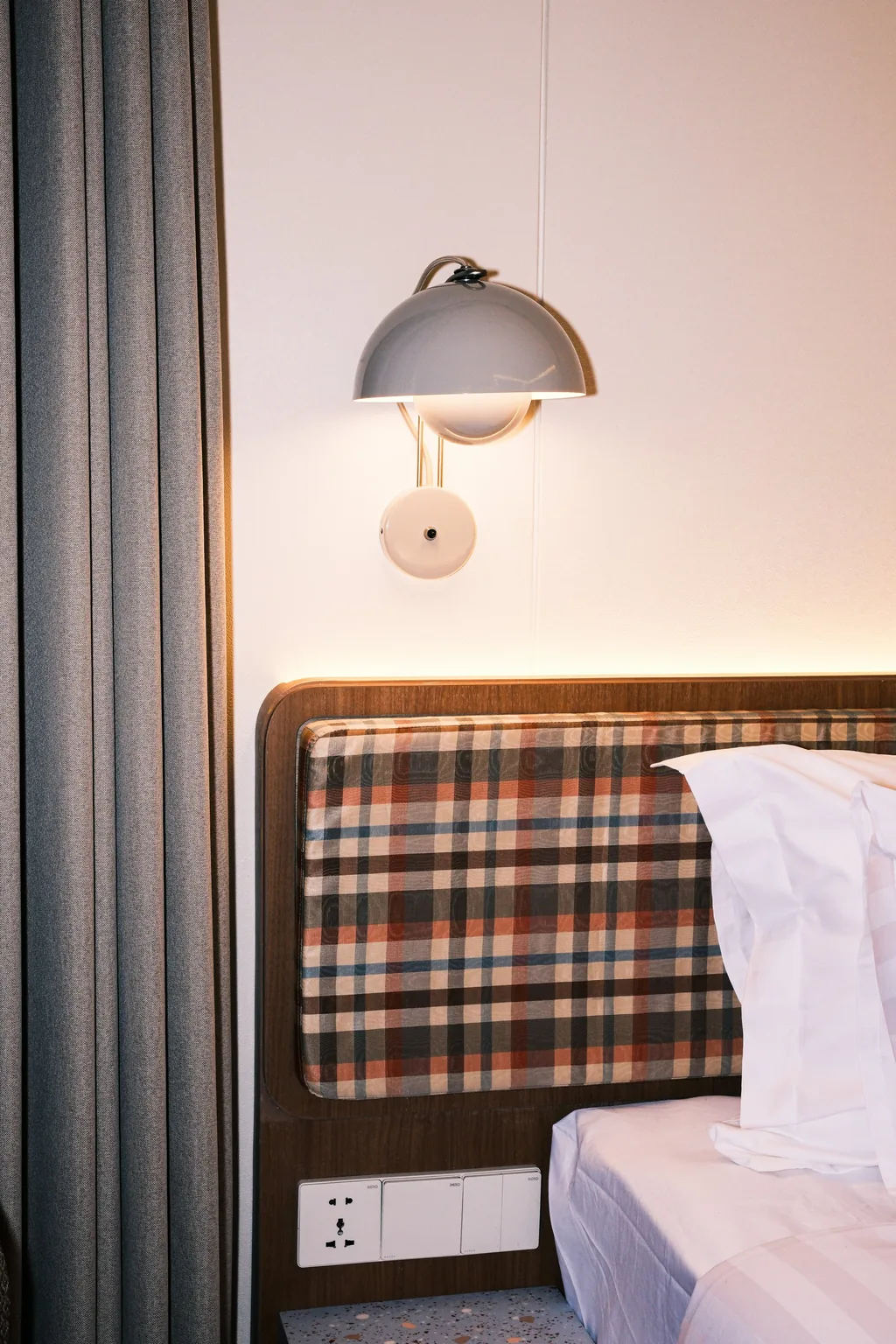 Plaid headboard with a wall lamp in a Volume Hotel room